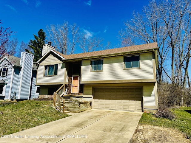 bi-level home with driveway, a chimney, a front yard, and a garage