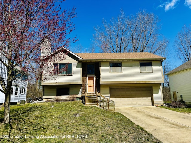 split foyer home with driveway, entry steps, a chimney, a front yard, and a garage
