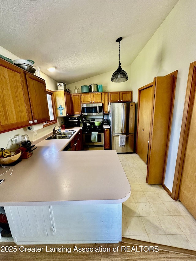 kitchen featuring pendant lighting, brown cabinets, a sink, stainless steel appliances, and a peninsula