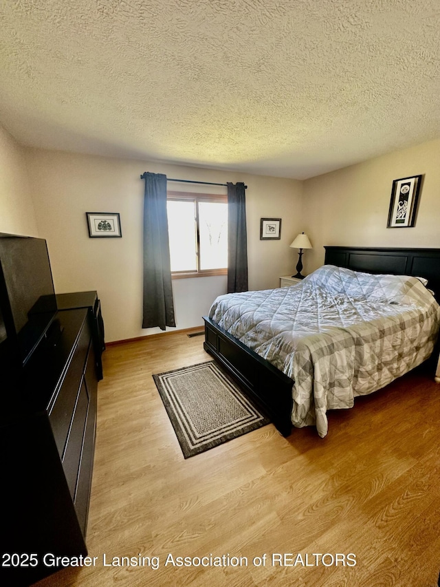 bedroom featuring wood finished floors and a textured ceiling