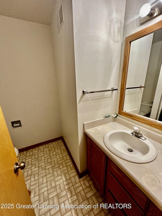 bathroom with visible vents, vanity, brick patterned floor, and baseboards