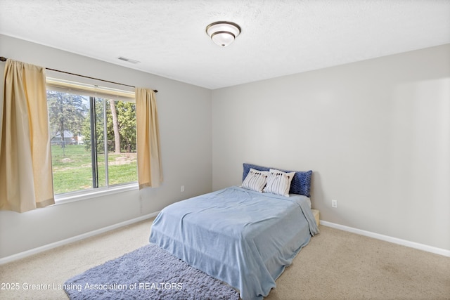 carpeted bedroom featuring baseboards, a textured ceiling, and visible vents
