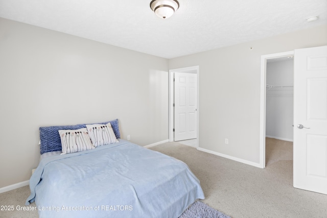 carpeted bedroom with baseboards, a closet, and a walk in closet
