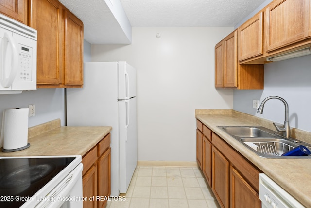 kitchen featuring a sink, white appliances, light countertops, a textured ceiling, and baseboards