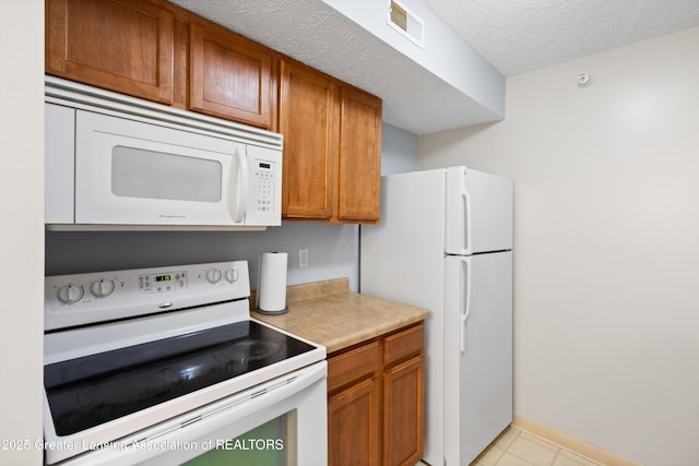 kitchen with white appliances, visible vents, brown cabinetry, and light countertops