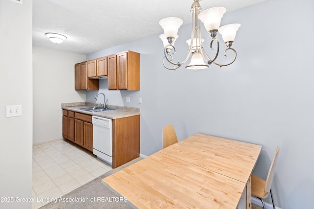 kitchen featuring white dishwasher, brown cabinets, light countertops, a sink, and a notable chandelier