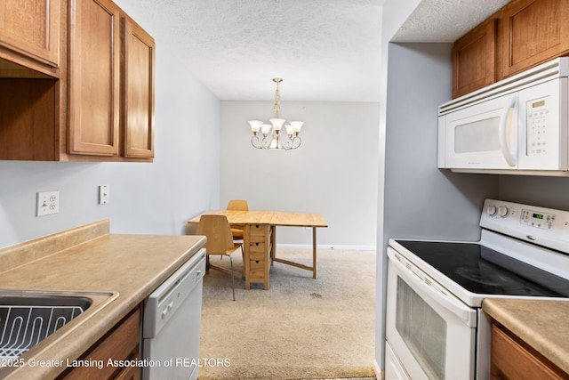 kitchen with brown cabinets, light colored carpet, white appliances, a chandelier, and decorative light fixtures