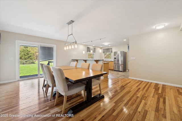 dining space with baseboards, track lighting, and light wood-type flooring