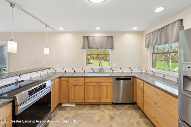 kitchen with appliances with stainless steel finishes, hanging light fixtures, a sink, stone counters, and recessed lighting
