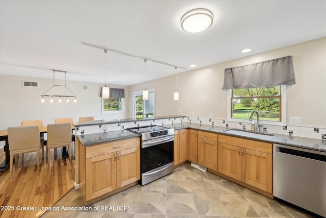 kitchen with visible vents, dark stone counters, a sink, appliances with stainless steel finishes, and a wealth of natural light