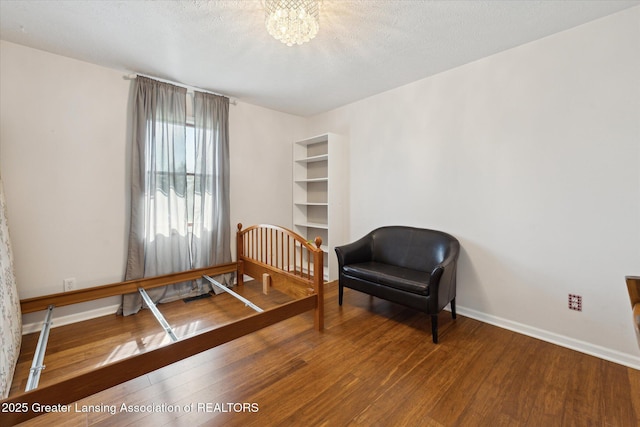 bedroom featuring an inviting chandelier, baseboards, and wood finished floors
