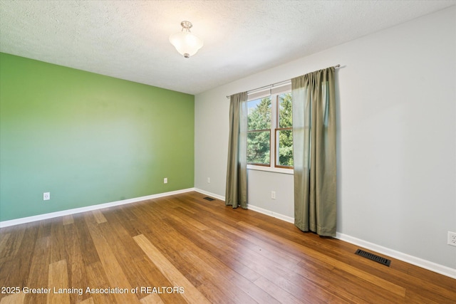 spare room featuring visible vents, baseboards, and wood finished floors