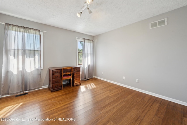 interior space with a textured ceiling, visible vents, and hardwood / wood-style floors