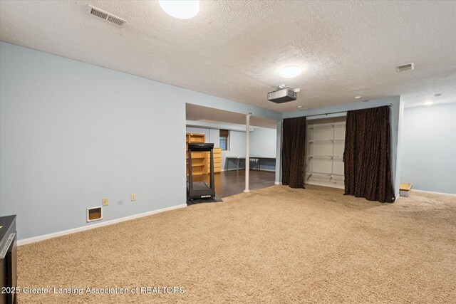 interior space with carpet floors, a textured ceiling, and visible vents