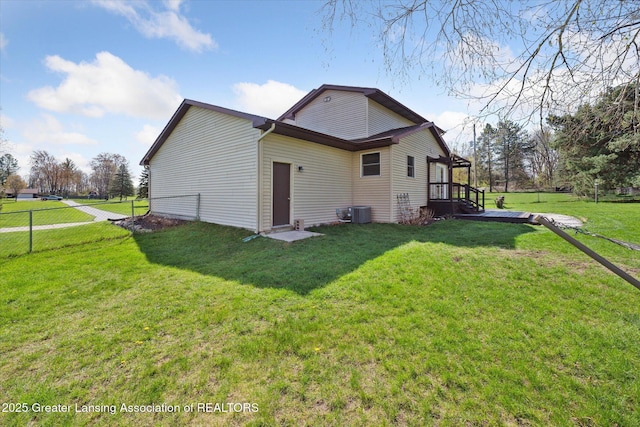rear view of house with a yard, a deck, central AC, and fence