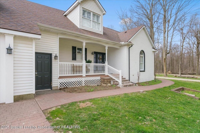 1785 N Williamston Rd, Williamston, MI 48895 - view of front of home with covered porch, brick siding, a front lawn, and roof with shingles