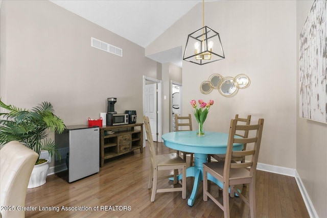 1785 N Williamston Rd, Williamston, MI 48895 - dining room featuring a notable chandelier, visible vents, baseboards, wood finished floors, and high vaulted ceiling