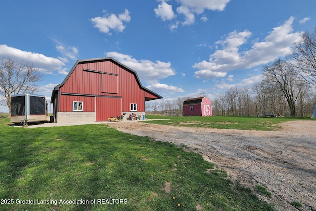 view of barn featuring a lawn and dirt driveway