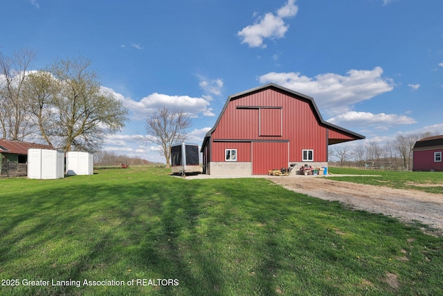 view of barn with driveway and a lawn