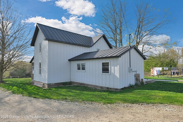 view of property exterior featuring a lawn, a standing seam roof, metal roof, and board and batten siding