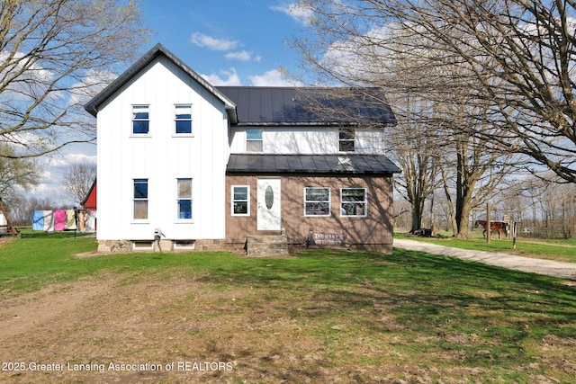 exterior space featuring a standing seam roof, a yard, board and batten siding, and metal roof
