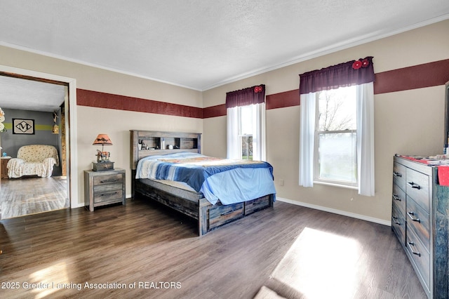 bedroom featuring a textured ceiling, wood finished floors, crown molding, and baseboards