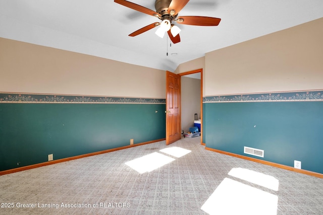 carpeted empty room with lofted ceiling, visible vents, ceiling fan, and baseboards