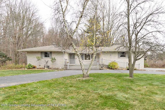 ranch-style house with covered porch, driveway, a front lawn, and brick siding