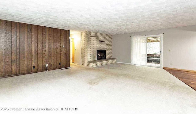 unfurnished living room with baseboards, a brick fireplace, wood walls, and a textured ceiling