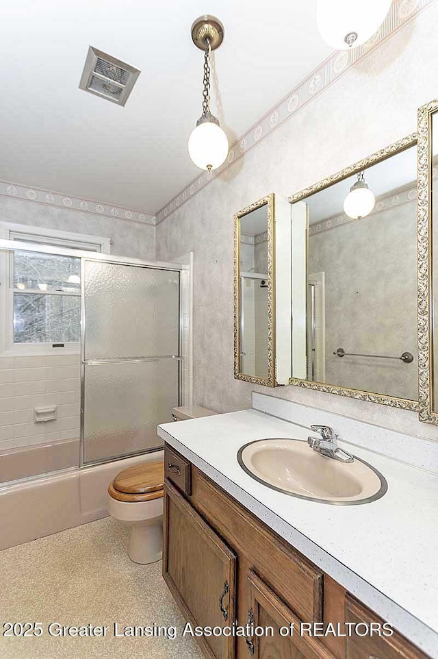 bathroom with enclosed tub / shower combo, toilet, visible vents, and vanity