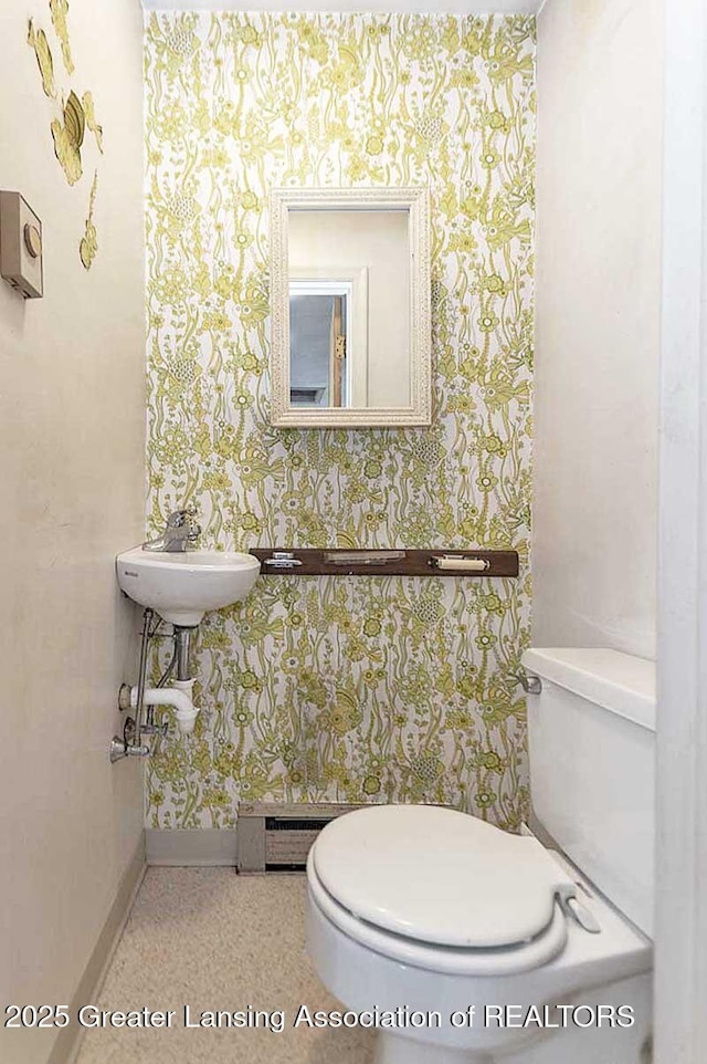 bathroom featuring toilet, wallpapered walls, and baseboards