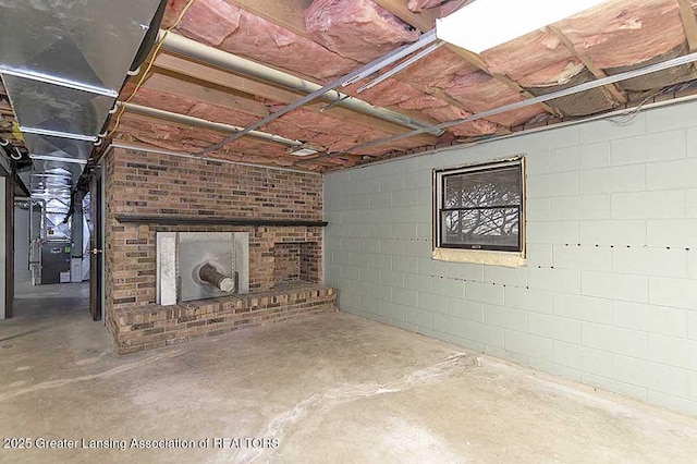 unfinished basement with heating unit and a brick fireplace