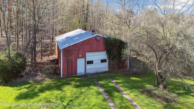 view of outbuilding with an outdoor structure, driveway, and a wooded view