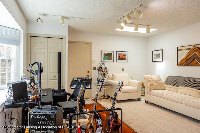 interior space with a textured ceiling, rail lighting, and wood finished floors
