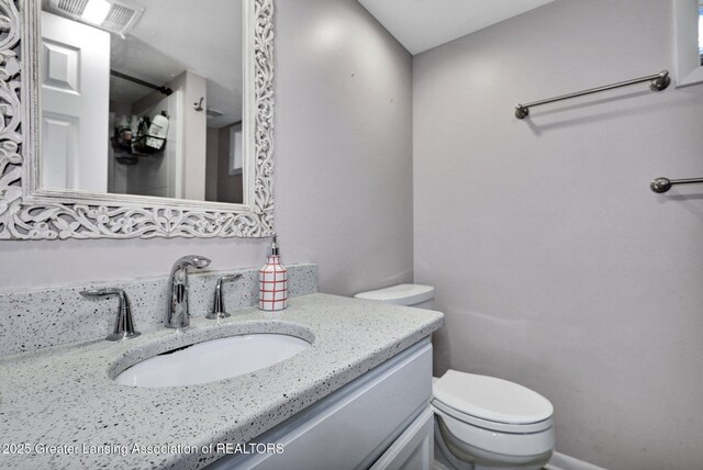 bathroom featuring vanity, toilet, and visible vents