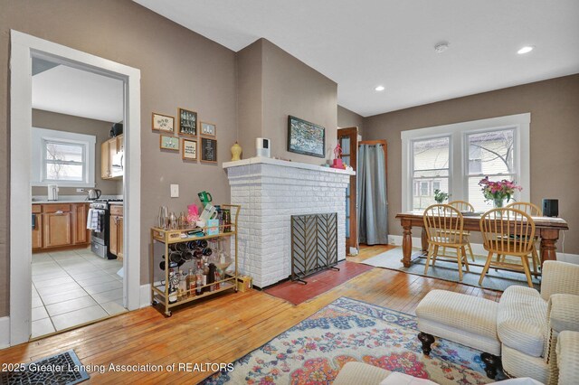 living room with light wood-style floors, recessed lighting, baseboards, and a brick fireplace