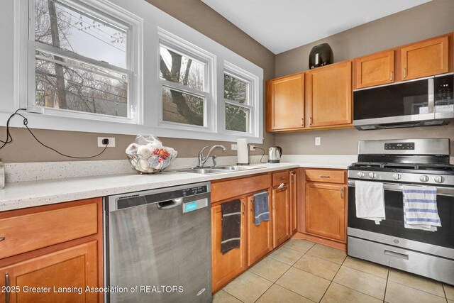 kitchen with a sink, appliances with stainless steel finishes, light tile patterned floors, and light countertops
