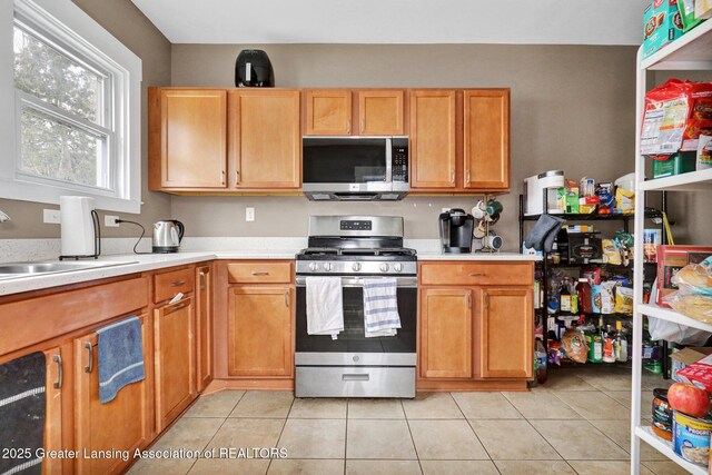 kitchen featuring light countertops, light tile patterned floors, stainless steel appliances, and a sink
