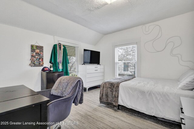 bedroom featuring multiple windows, carpet, a textured ceiling, and lofted ceiling