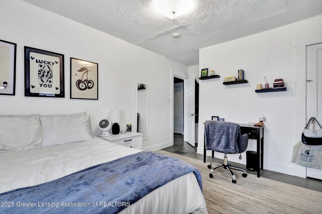 bedroom with baseboards, a textured ceiling, and wood finished floors