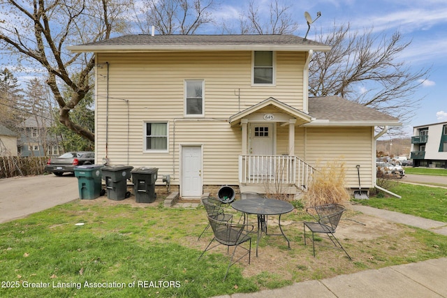 view of front of property featuring a shingled roof and a front yard