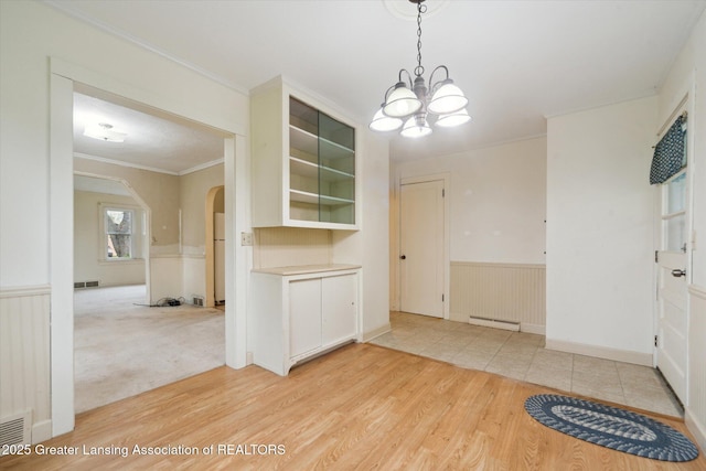 12102 Rupp Rd, Grand Ledge, MI 48837 - unfurnished dining area with arched walkways, a chandelier, light wood-style flooring, crown molding, and a wainscoted wall