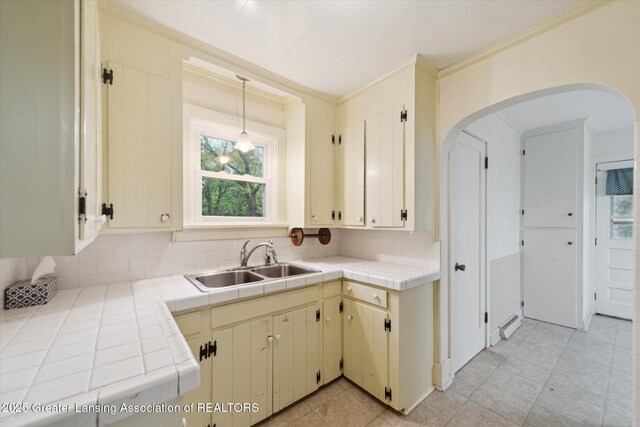 12102 Rupp Rd, Grand Ledge, MI 48837 - kitchen with a sink, tile countertops, tasteful backsplash, arched walkways, and ornamental molding