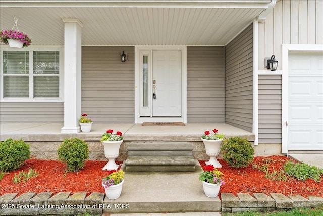 609 E Avocet Dr, East Lansing, MI 48823 - entrance to property featuring covered porch, board and batten siding, and a garage