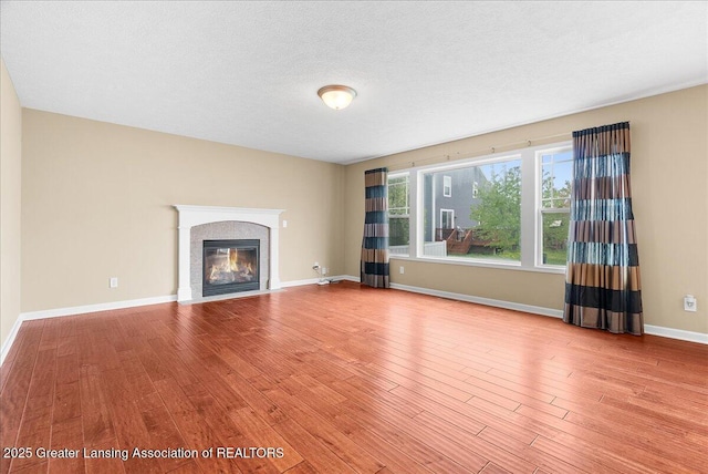 609 E Avocet Dr, East Lansing, MI 48823 - unfurnished living room with wood finished floors, baseboards, and a fireplace with flush hearth