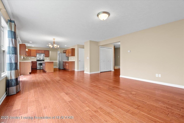 609 E Avocet Dr, East Lansing, MI 48823 - unfurnished living room featuring a chandelier, baseboards, light wood-type flooring, a sink, and recessed lighting