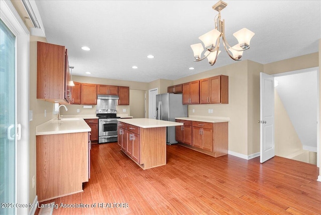 609 E Avocet Dr, East Lansing, MI 48823 - kitchen with appliances with stainless steel finishes, under cabinet range hood, light wood-style floors, light countertops, and a kitchen island