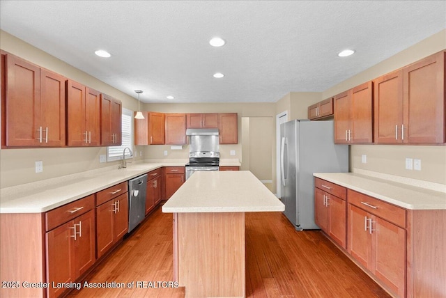 609 E Avocet Dr, East Lansing, MI 48823 - kitchen with stainless steel appliances, a sink, under cabinet range hood, a kitchen island, and light countertops