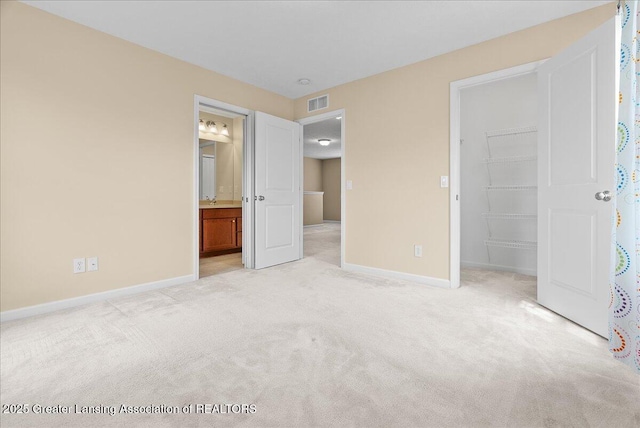 609 E Avocet Dr, East Lansing, MI 48823 - unfurnished bedroom with a spacious closet, light carpet, baseboards, a closet, and ensuite bathroom