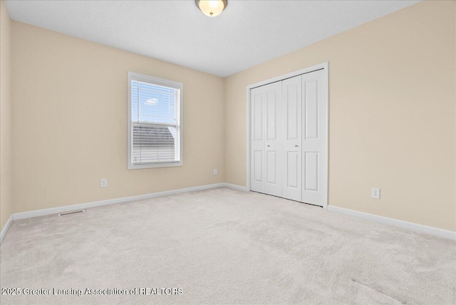 609 E Avocet Dr, East Lansing, MI 48823 - unfurnished bedroom featuring baseboards, carpet, and a closet